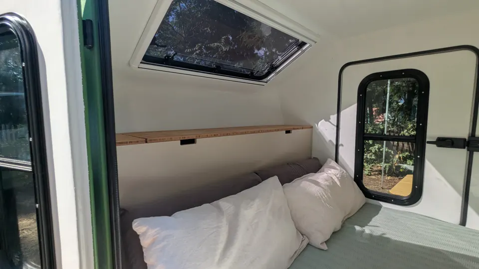 Bett mit Leinenkissen unter dem geöffneten Dachfenster
