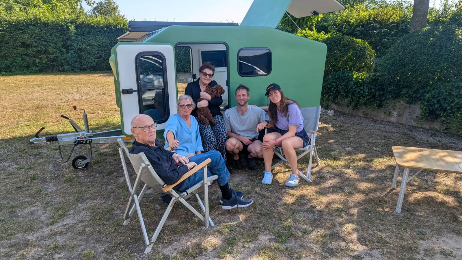 Familie und Freunde sitzen vor dem grünen Glide auf einer Wiese
